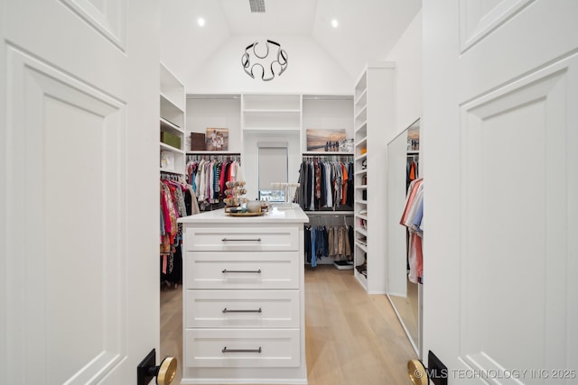 walk in closet featuring high vaulted ceiling and light hardwood / wood-style floors