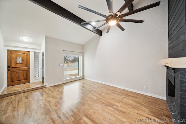 unfurnished living room featuring a brick fireplace, ceiling fan, light hardwood / wood-style flooring, and vaulted ceiling with beams