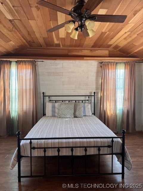 bedroom featuring wood walls, wood-type flooring, vaulted ceiling, and wooden ceiling