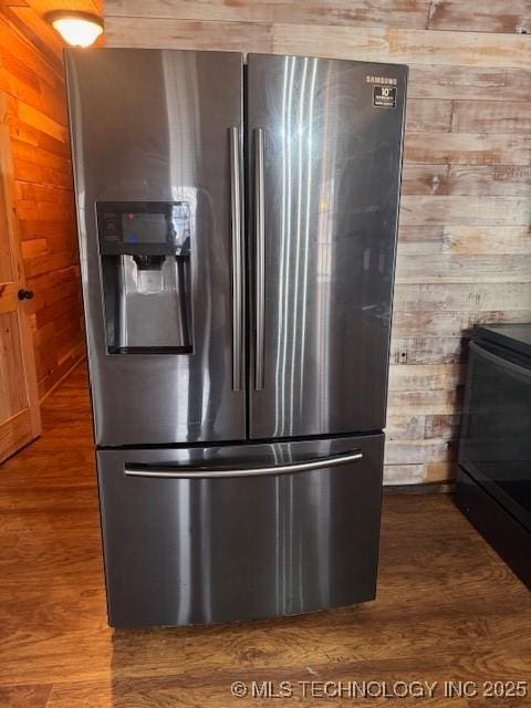 kitchen with hardwood / wood-style flooring, stove, wood walls, and stainless steel fridge with ice dispenser