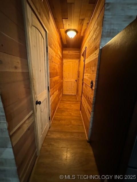 hall featuring wood-type flooring, wooden ceiling, and wooden walls