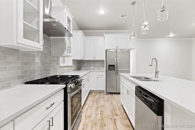 kitchen with pendant lighting, sink, wall chimney range hood, stainless steel appliances, and white cabinets