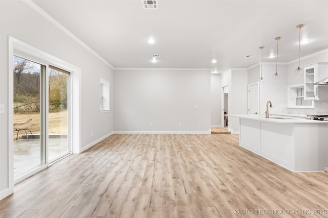 unfurnished living room with crown molding, sink, and light wood-type flooring