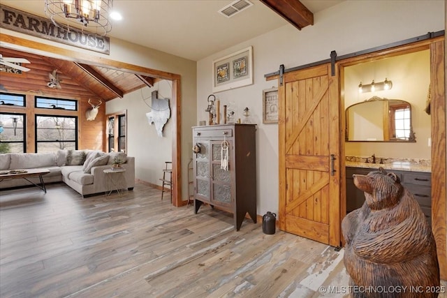 living room featuring hardwood / wood-style flooring, a barn door, vaulted ceiling with beams, and wood ceiling