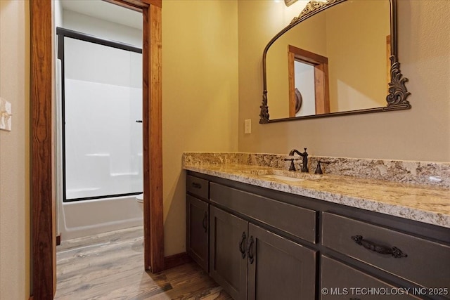 full bathroom featuring vanity, hardwood / wood-style floors, shower / bath combination with glass door, and toilet