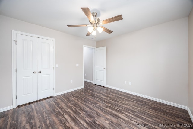 unfurnished bedroom featuring dark hardwood / wood-style flooring, ceiling fan, and a closet