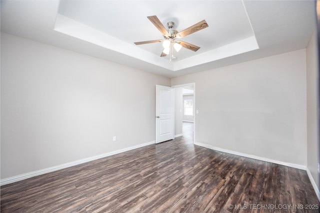 unfurnished room featuring a tray ceiling, dark wood-type flooring, and ceiling fan