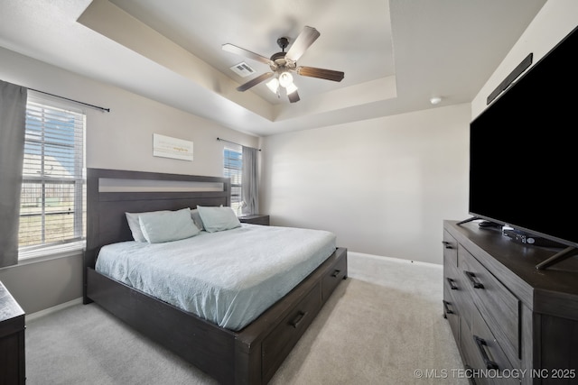 bedroom featuring a tray ceiling, light colored carpet, and baseboards