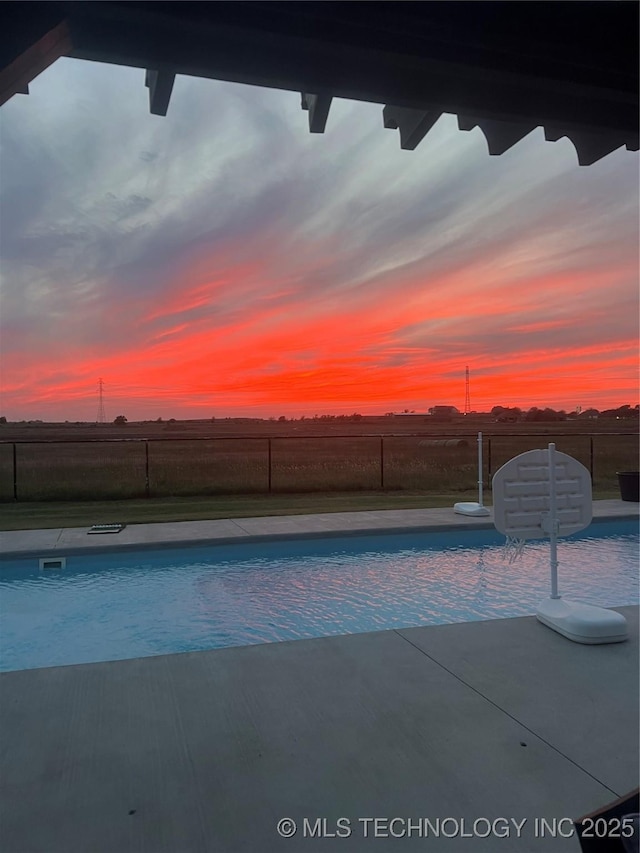 pool at dusk with fence and a fenced in pool