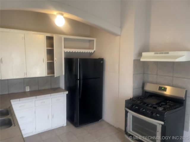 kitchen with white cabinetry, black fridge, tile counters, and stainless steel gas range