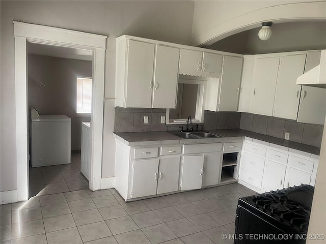 kitchen featuring light tile patterned flooring, tile countertops, white cabinetry, sink, and black gas range