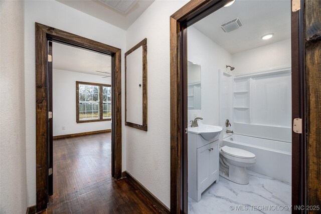 719 W Evergreen, Durant, OK 74701 - hallway with a sink, baseboards, visible vents, and wood finished floors