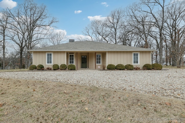 single story home featuring a chimney, a front lawn, and board and batten siding