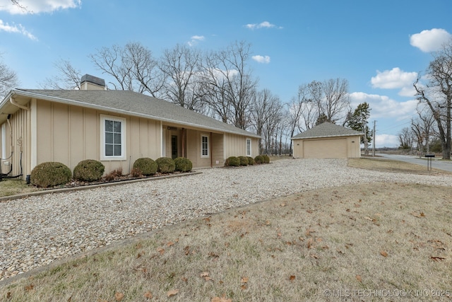 ranch-style home with a chimney, a detached garage, and board and batten siding