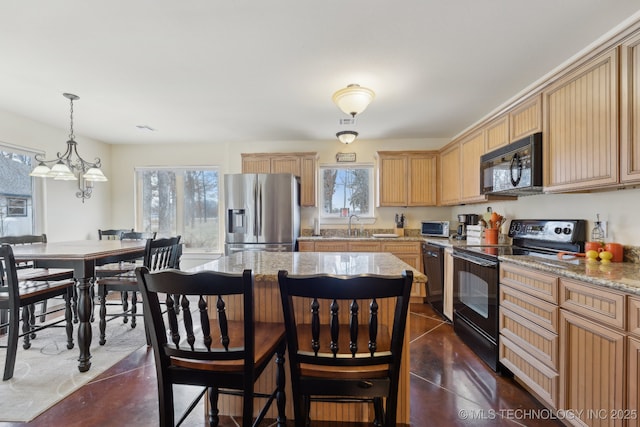 kitchen featuring light stone counters, a center island, concrete flooring, black appliances, and pendant lighting