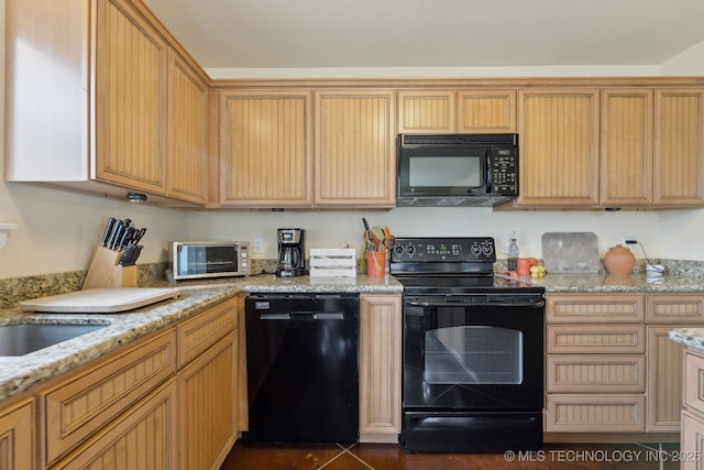 kitchen with light stone counters, a toaster, a sink, and black appliances