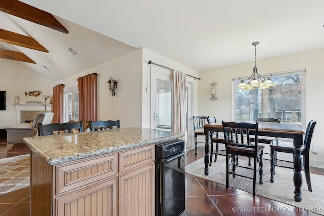 kitchen with lofted ceiling with beams, open floor plan, hanging light fixtures, a lit fireplace, and a center island
