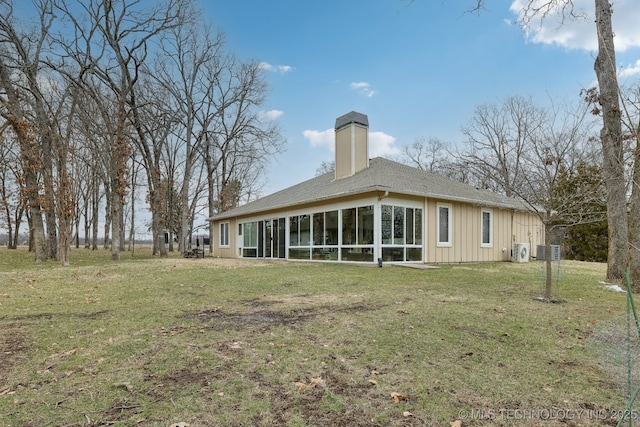 rear view of property featuring board and batten siding, a sunroom, a yard, and a chimney