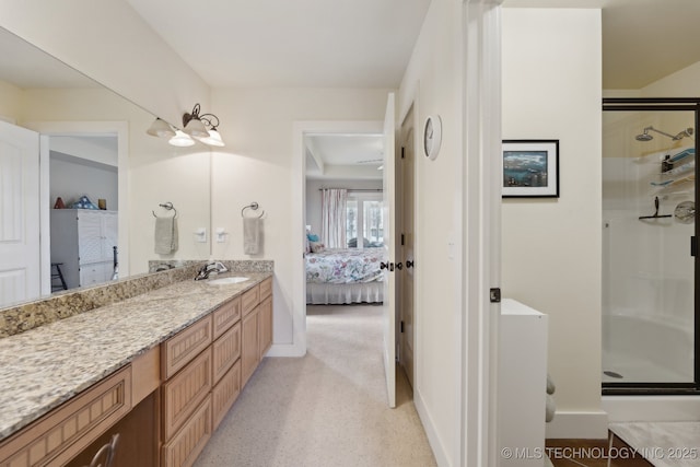 ensuite bathroom with ensuite bathroom, a shower stall, vanity, and baseboards