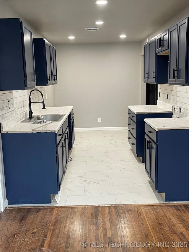 kitchen featuring a sink, blue cabinets, baseboards, and light countertops