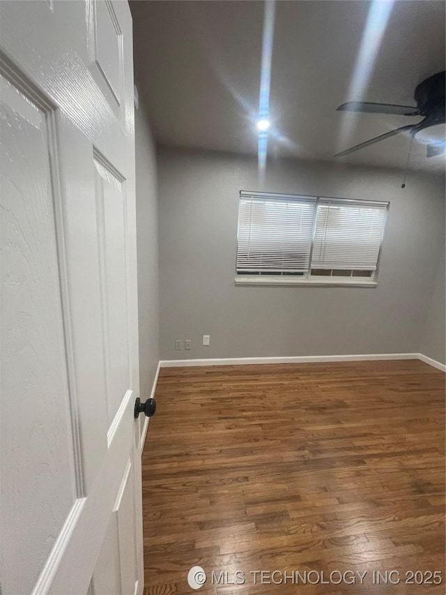 empty room with baseboards, wood finished floors, and a ceiling fan