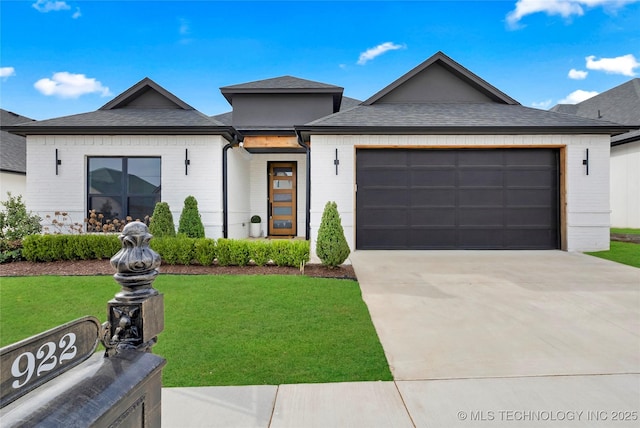 view of front of property featuring an attached garage, a front yard, brick siding, roof with shingles, and driveway