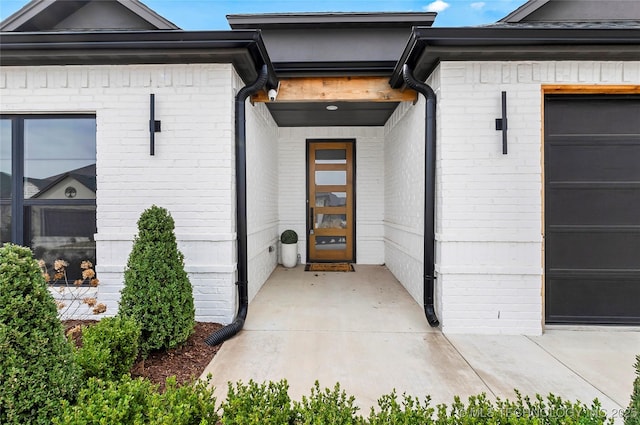 view of exterior entry featuring brick siding and an attached garage