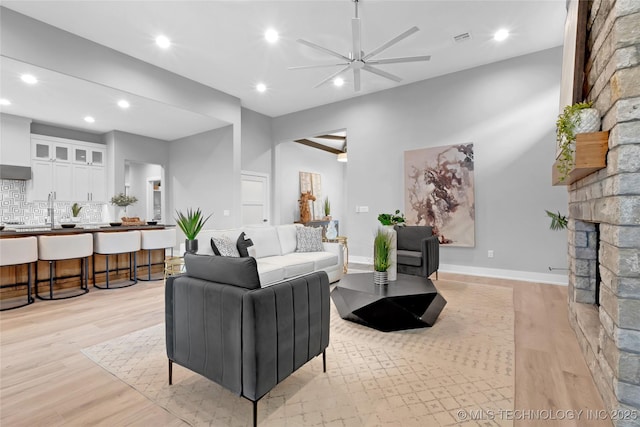 living area with visible vents, light wood-style flooring, ceiling fan, recessed lighting, and a stone fireplace