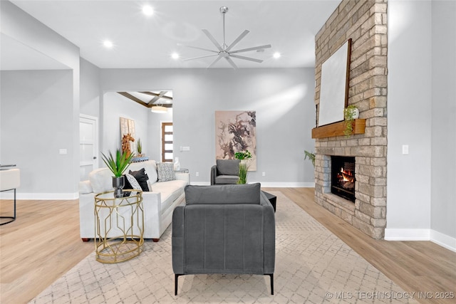 living room featuring recessed lighting, baseboards, light wood finished floors, ceiling fan, and a brick fireplace