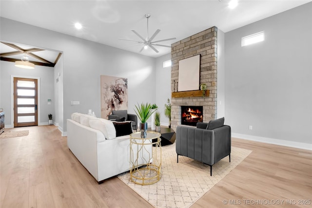living room featuring a brick fireplace, baseboards, ceiling fan, and light wood-type flooring