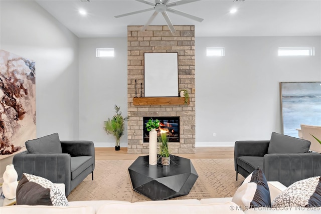 living area featuring baseboards, a fireplace, wood finished floors, and ceiling fan