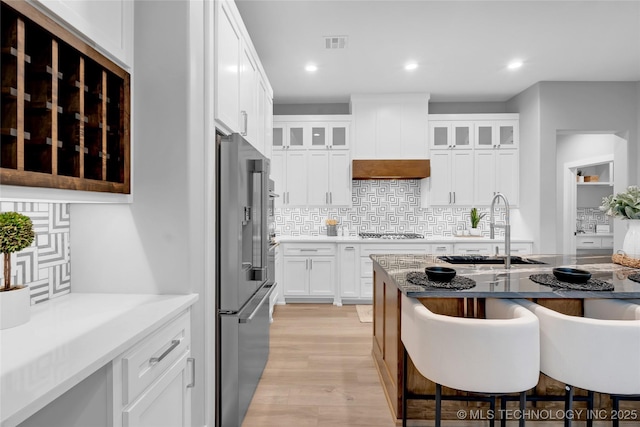 kitchen featuring visible vents, a breakfast bar, appliances with stainless steel finishes, a sink, and light wood-style floors