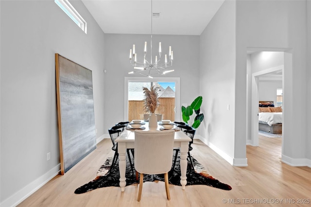dining room with light wood-style flooring, a notable chandelier, baseboards, and visible vents