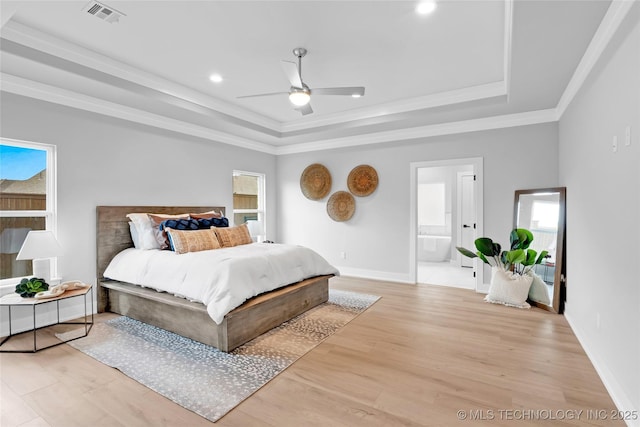 bedroom with visible vents, crown molding, light wood-style flooring, and a raised ceiling