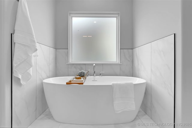 bathroom featuring tile walls and a freestanding bath