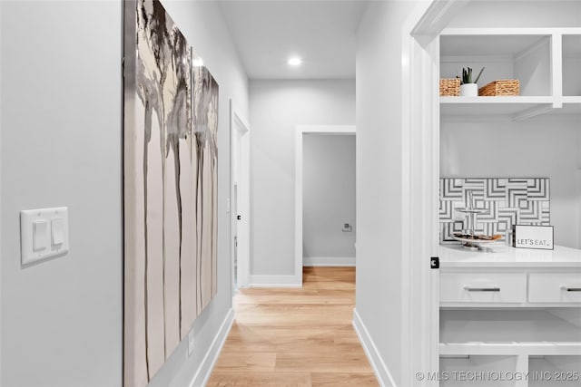 hall with light wood finished floors, baseboards, and recessed lighting