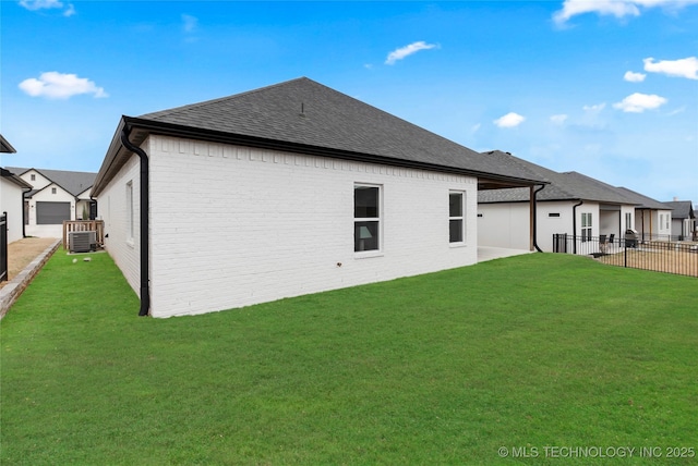 rear view of property with central AC unit, a lawn, fence, and brick siding