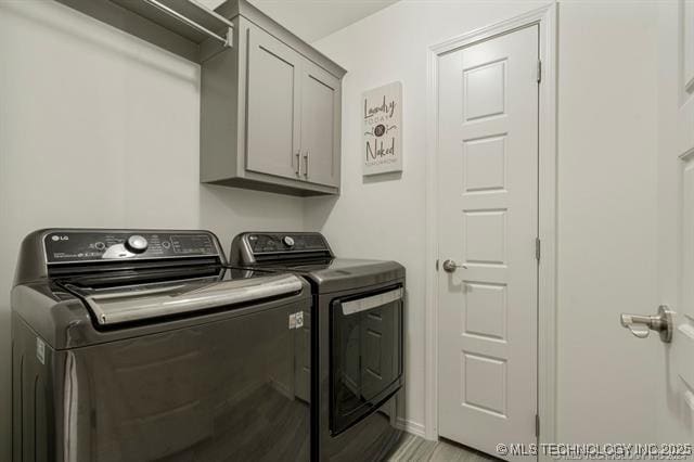 clothes washing area with cabinets and washer and dryer