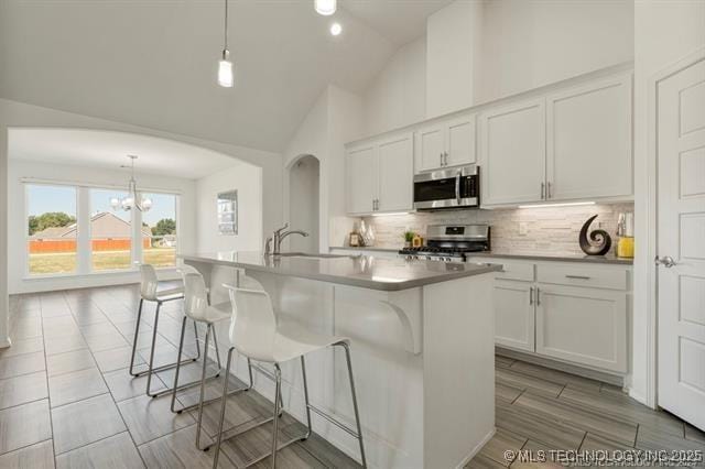 kitchen featuring white cabinetry, appliances with stainless steel finishes, pendant lighting, and a center island with sink