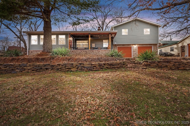 split level home featuring a garage, brick siding, and a chimney