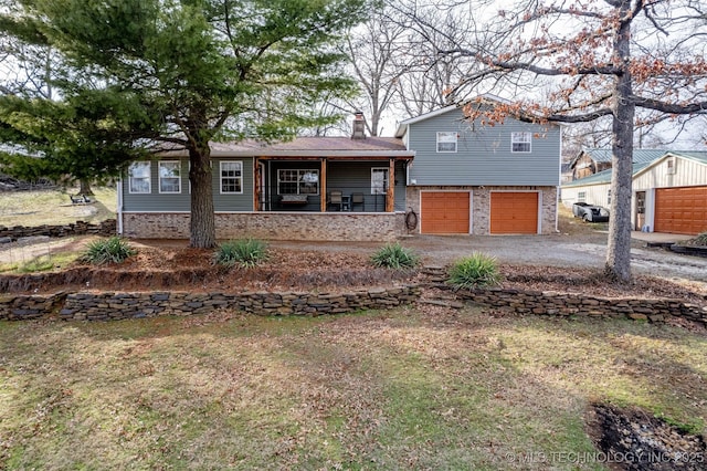 split level home with brick siding, a porch, a chimney, a garage, and driveway