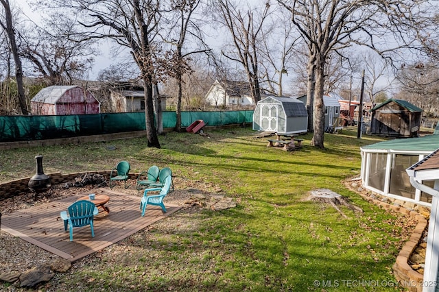 view of yard with a wooden deck, an outdoor structure, a storage shed, and a fenced backyard