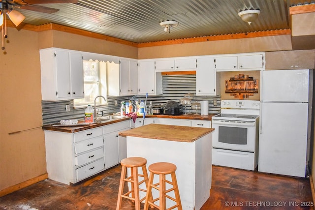 kitchen with a breakfast bar area, white appliances, a kitchen island, sink, and white cabinetry