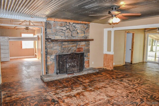 unfurnished living room featuring a ceiling fan and a stone fireplace