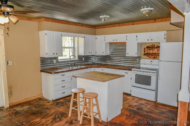 kitchen featuring backsplash, a sink, white appliances, dark countertops, and white cabinets