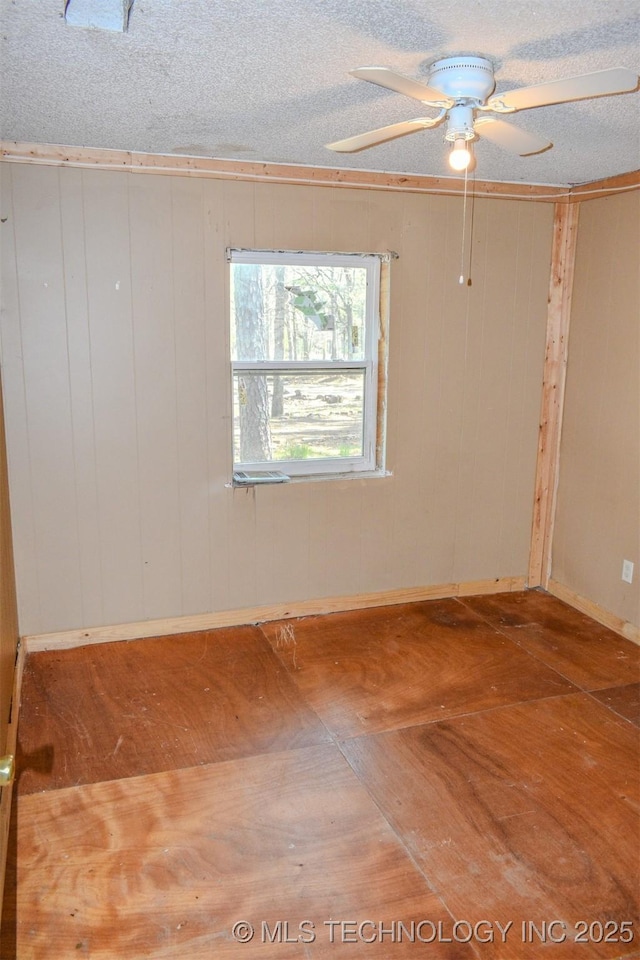 spare room with baseboards, a textured ceiling, wood finished floors, and a ceiling fan