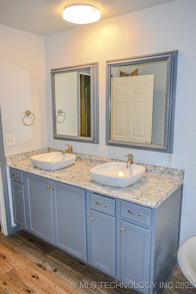 bathroom featuring double vanity, a sink, and wood finished floors
