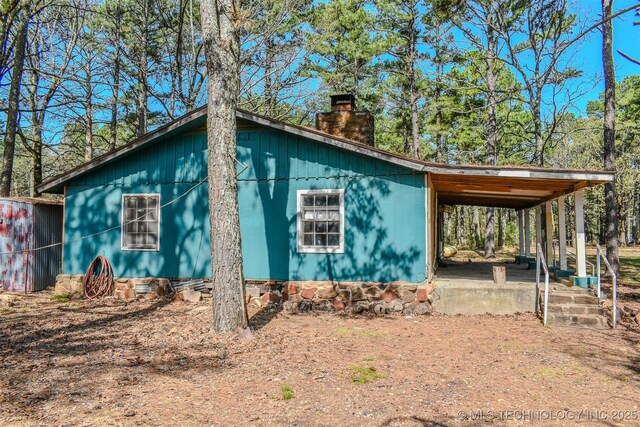 view of property exterior featuring a chimney and a carport