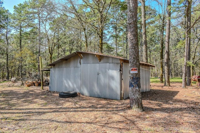 view of outbuilding featuring a wooded view and an outdoor structure