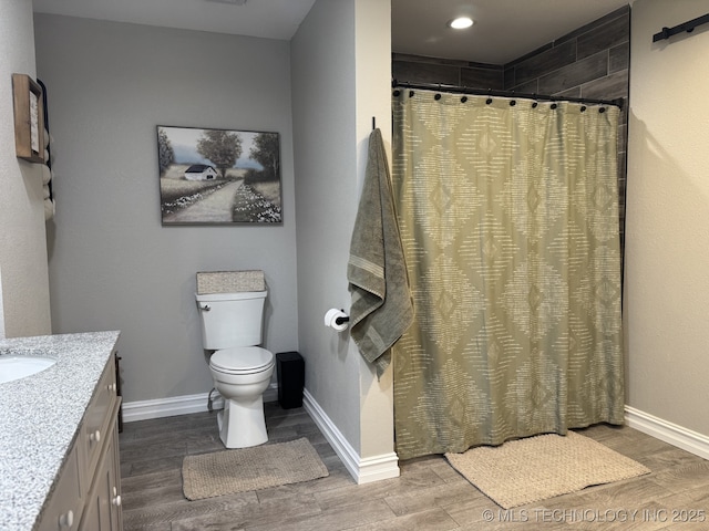 bathroom featuring hardwood / wood-style flooring, toilet, vanity, and curtained shower